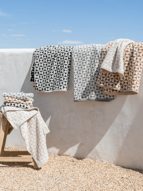 Harper bath towels in various colors hanging over ledge outside