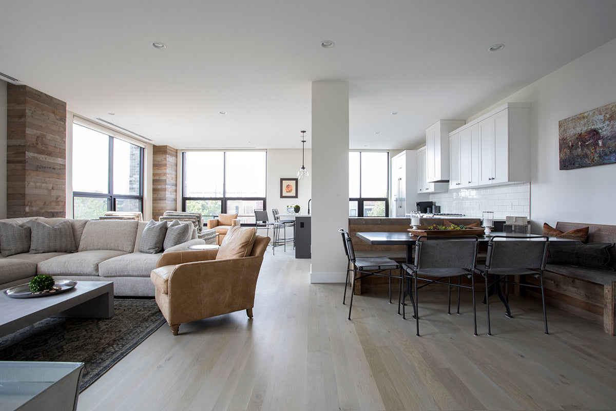 Modern apartment with big windows, living room, dining nook, kitchen and seating area.