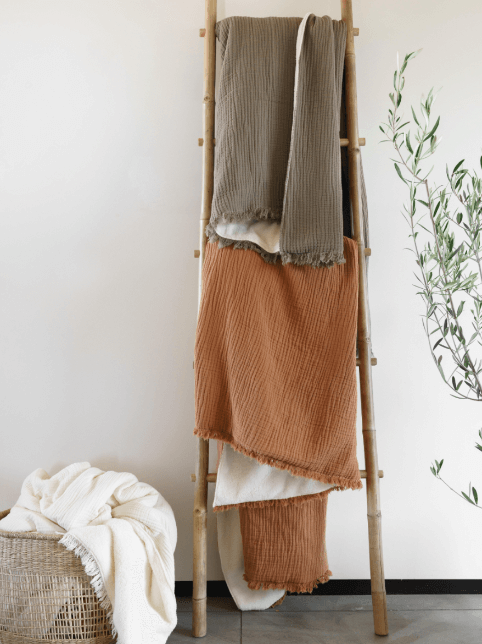 Alaia sherpa throw blankets in various colors on stand