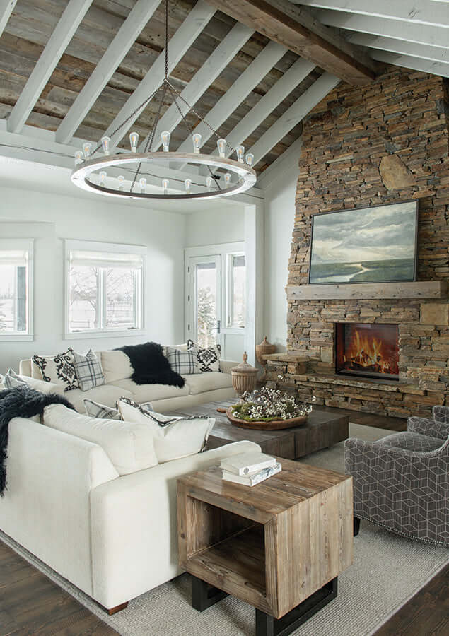 Rustic modern living room with stone fireplace, vaulted ceilings, and circular chandelier