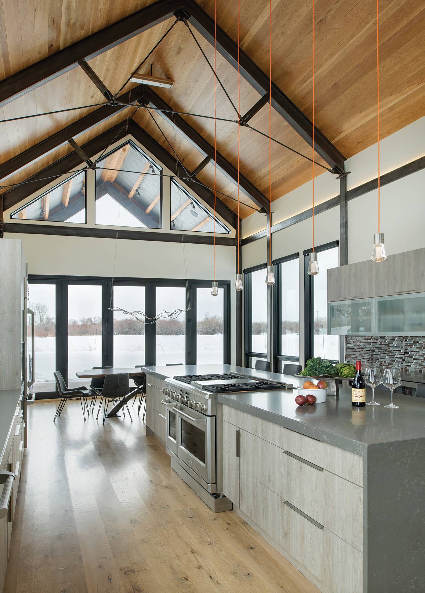 Modern kitchen with vaulted ceilings, a large island, and a wall of windows