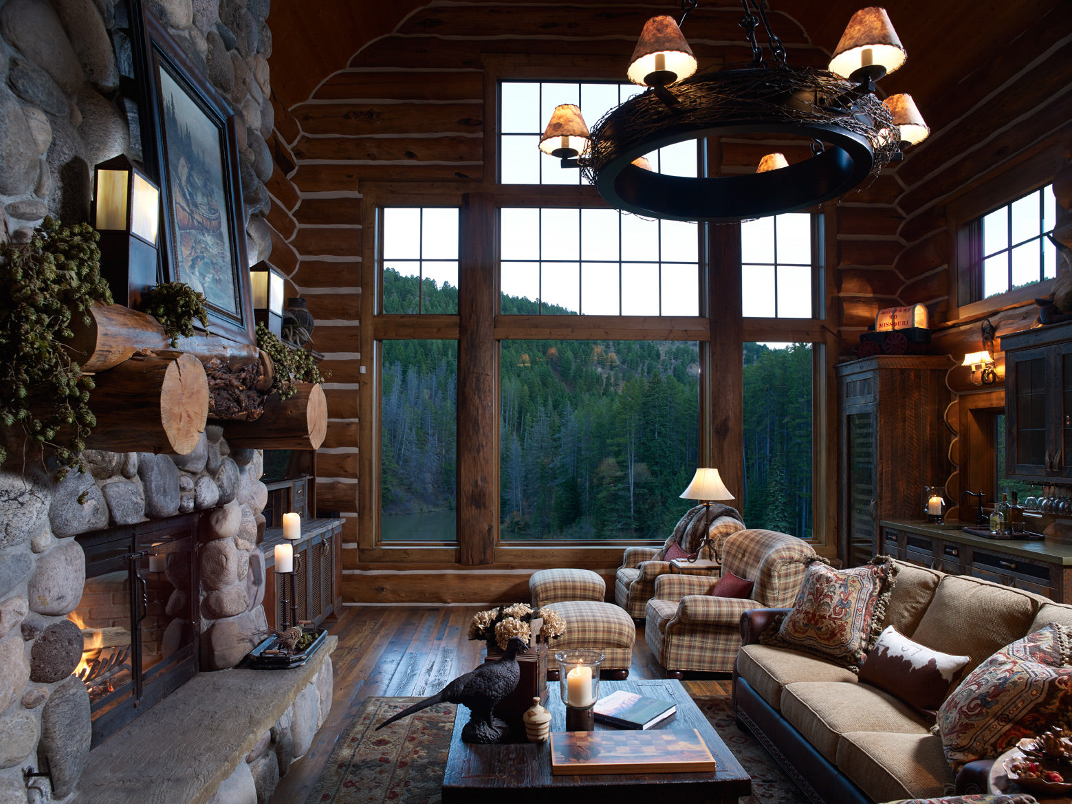 Living room with massive stone fireplace and large windows with mountain views